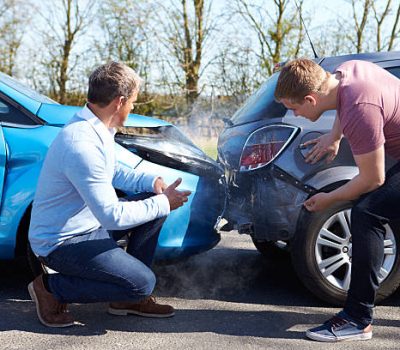 Two Drivers Arguing After Traffic Accident looking at damage